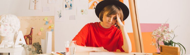 A frustrated artist sits in her studio upset about her creative block and burnout.