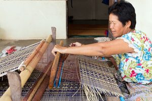 alt="Thai woman weaving cloth"