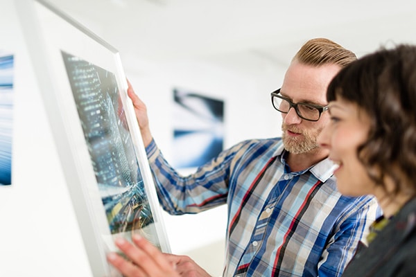 An artist shares his painting with a woman at a gallery.