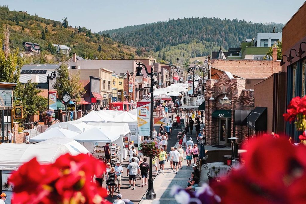 An art event or festival exists on a street with canopies and tents.