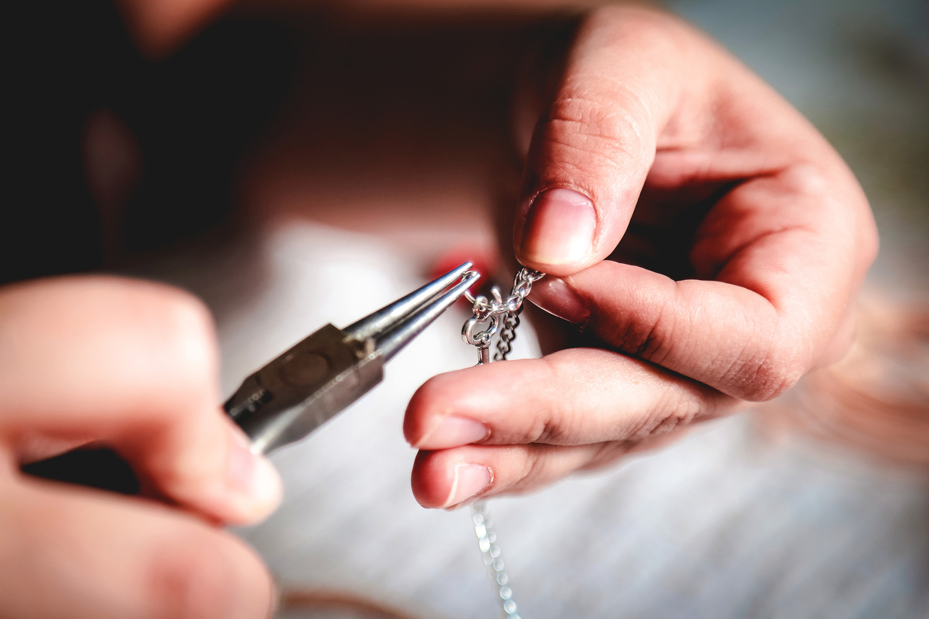 Jewelry being crafted with needle-nose pliers.