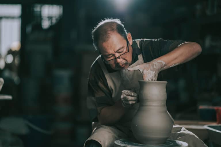 A sculptor works in a dark studio.