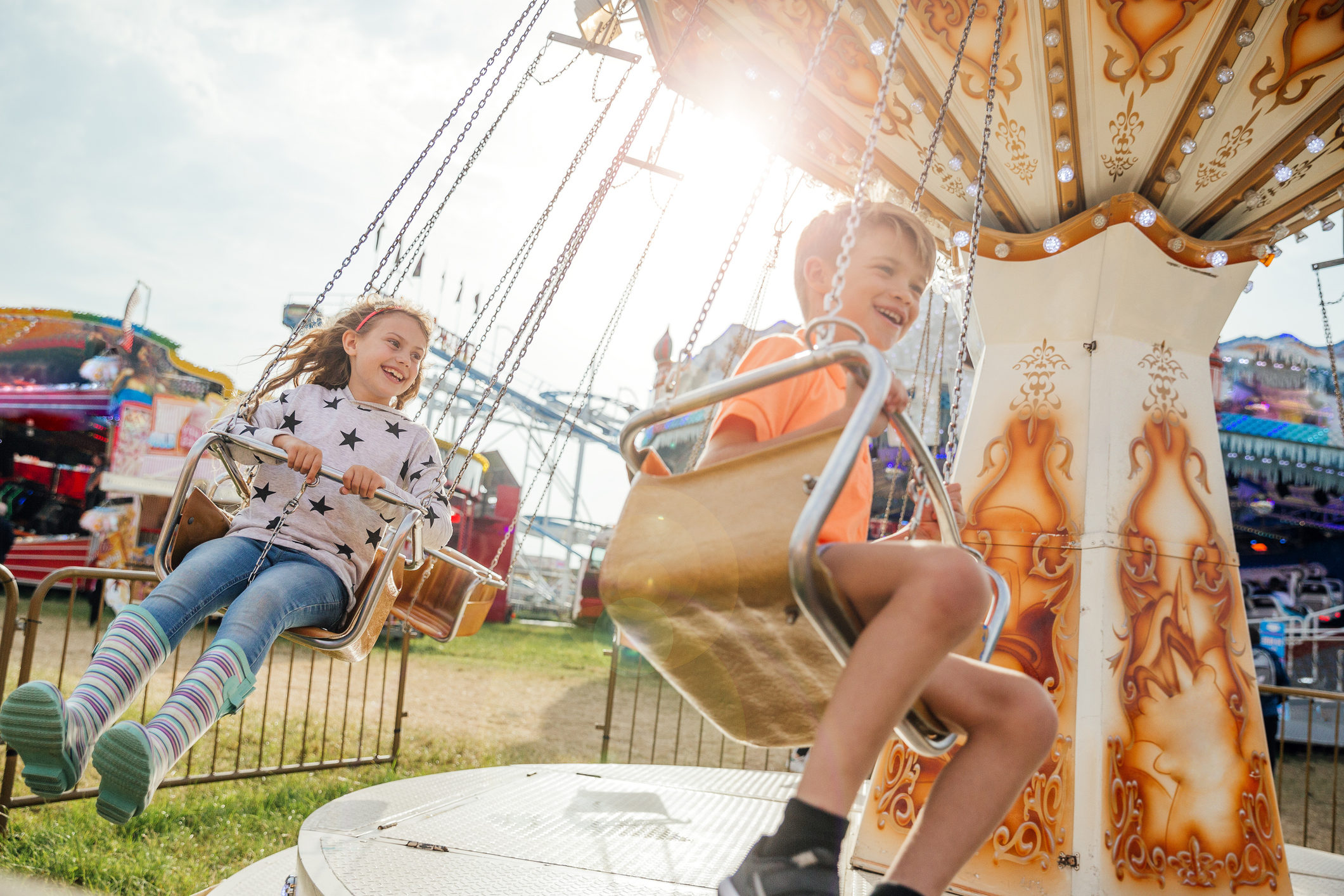 children ride a swinging carousel at an event.