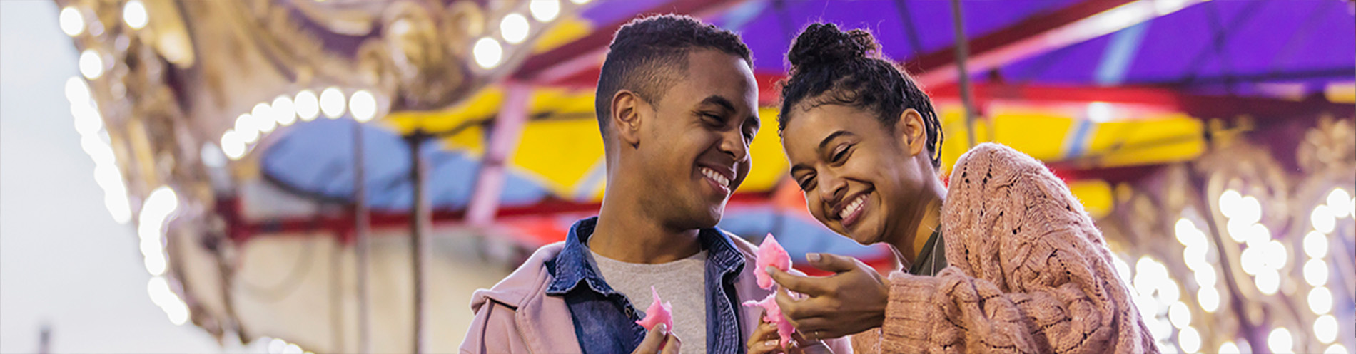 A couple eats cotton candy together at an event.