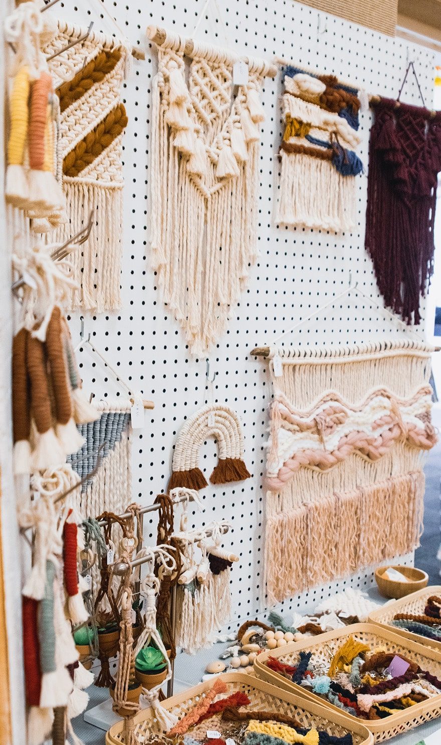 Macrame decor is hung in a simple white booth at a craft show.