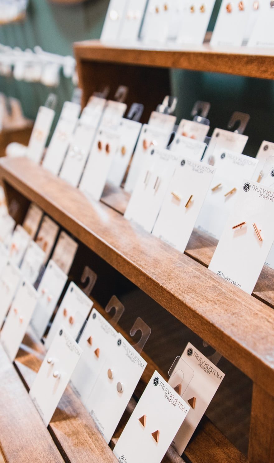 Rows of custom earrings sit on a wooden display in the Truly Kustom booth.