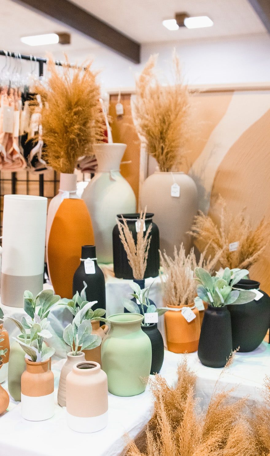 Hand painted pottery of varying sizes sit arranged on a white table in the Terracotta Studio booth.