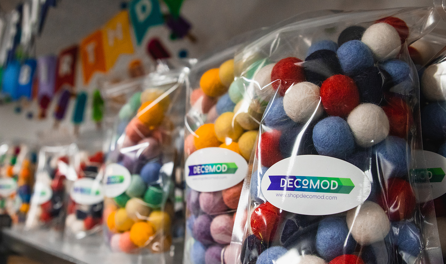 Colorful beaded garland sits packaged in clear bags on a shelf in the Decomod booth.