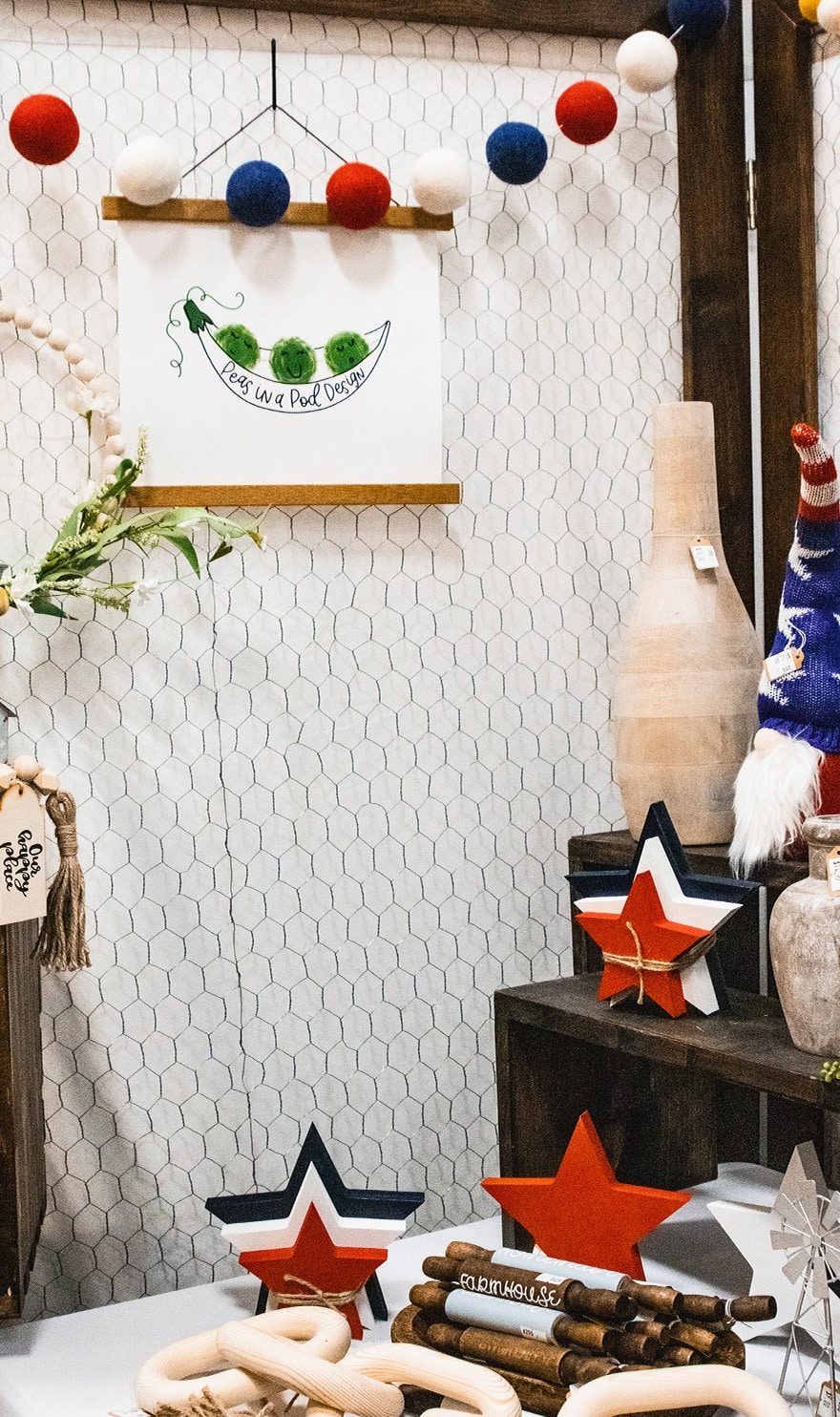 Handmade home decor sits on display on stands in the Peas in a Pod Design booth.