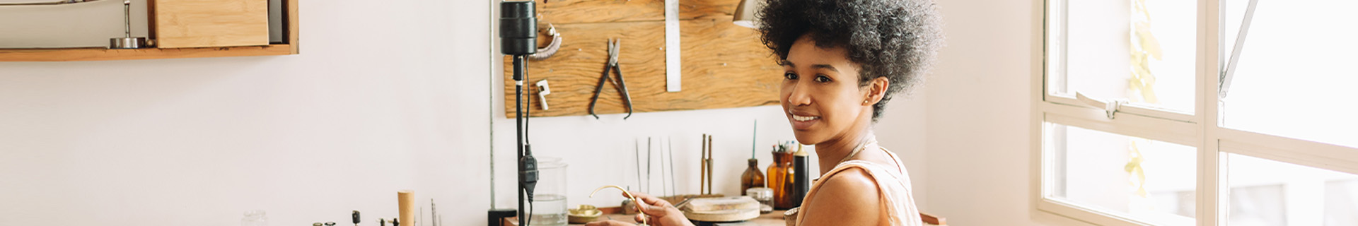 A jewelry maker crafts on a bench.