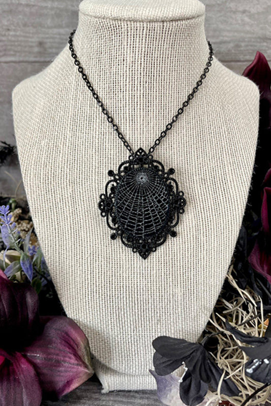 A black gothic pendant with a preserved spiderweb sits neatly on a fake bust so Laura can photograph the piece for her website.