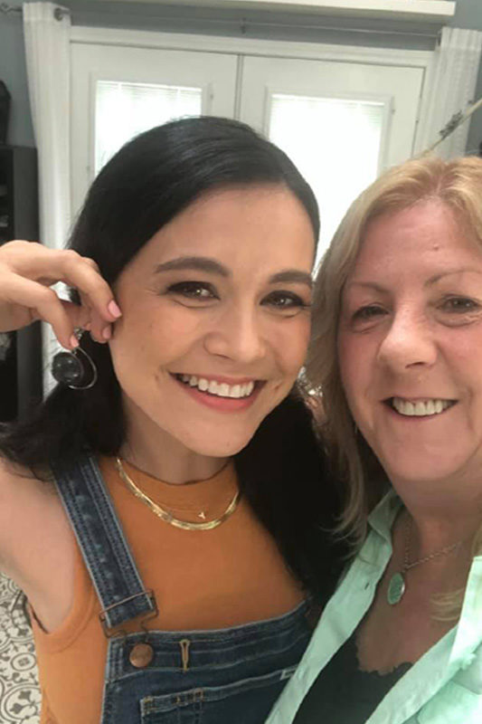 Laura posing with the host of the show "Makers Nation" for a selfie as they show off a new pair of spiderweb earrings.