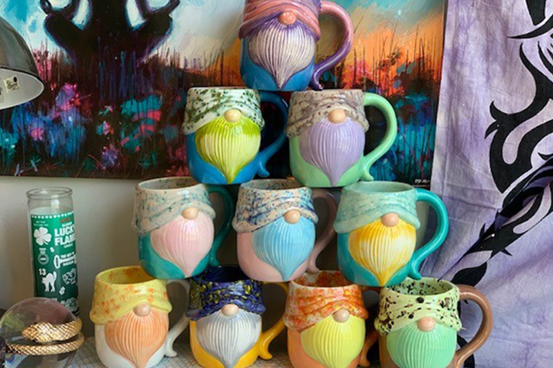 A stack of colorful gnome mugs sit atop a table in Marika's home studio
