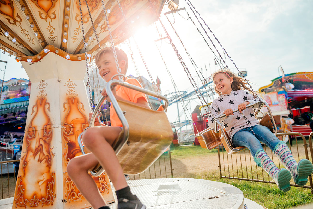 Children laugh on a ride at a festival.