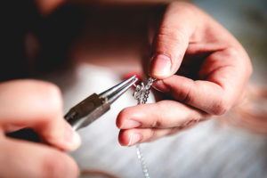 A jewelry maker makes products by hand.