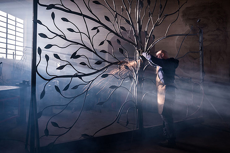 a metalworker sculpts a large art piece.