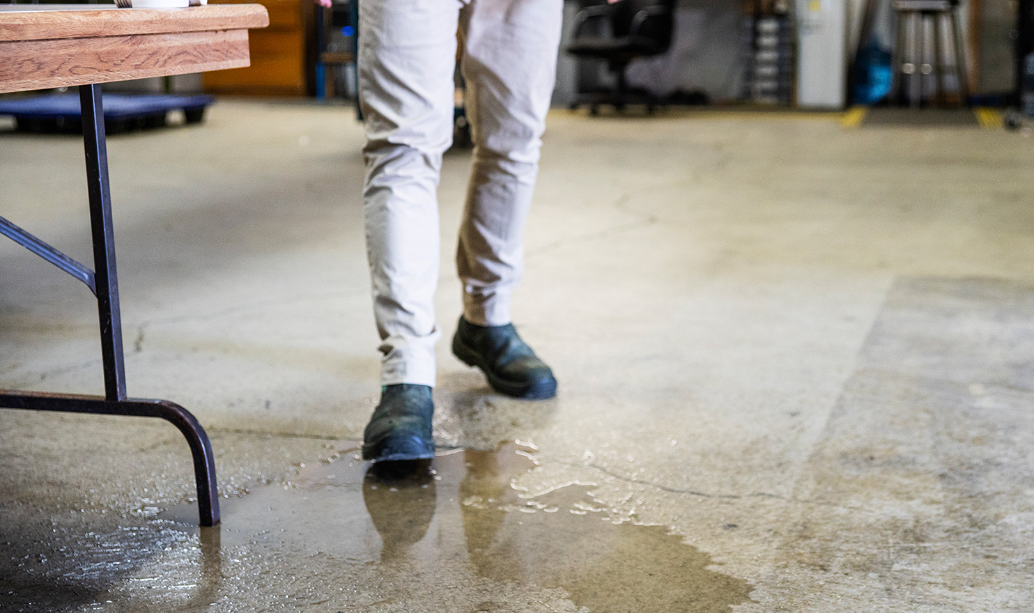 A man slipping on spilled water next to a folding table at an event.