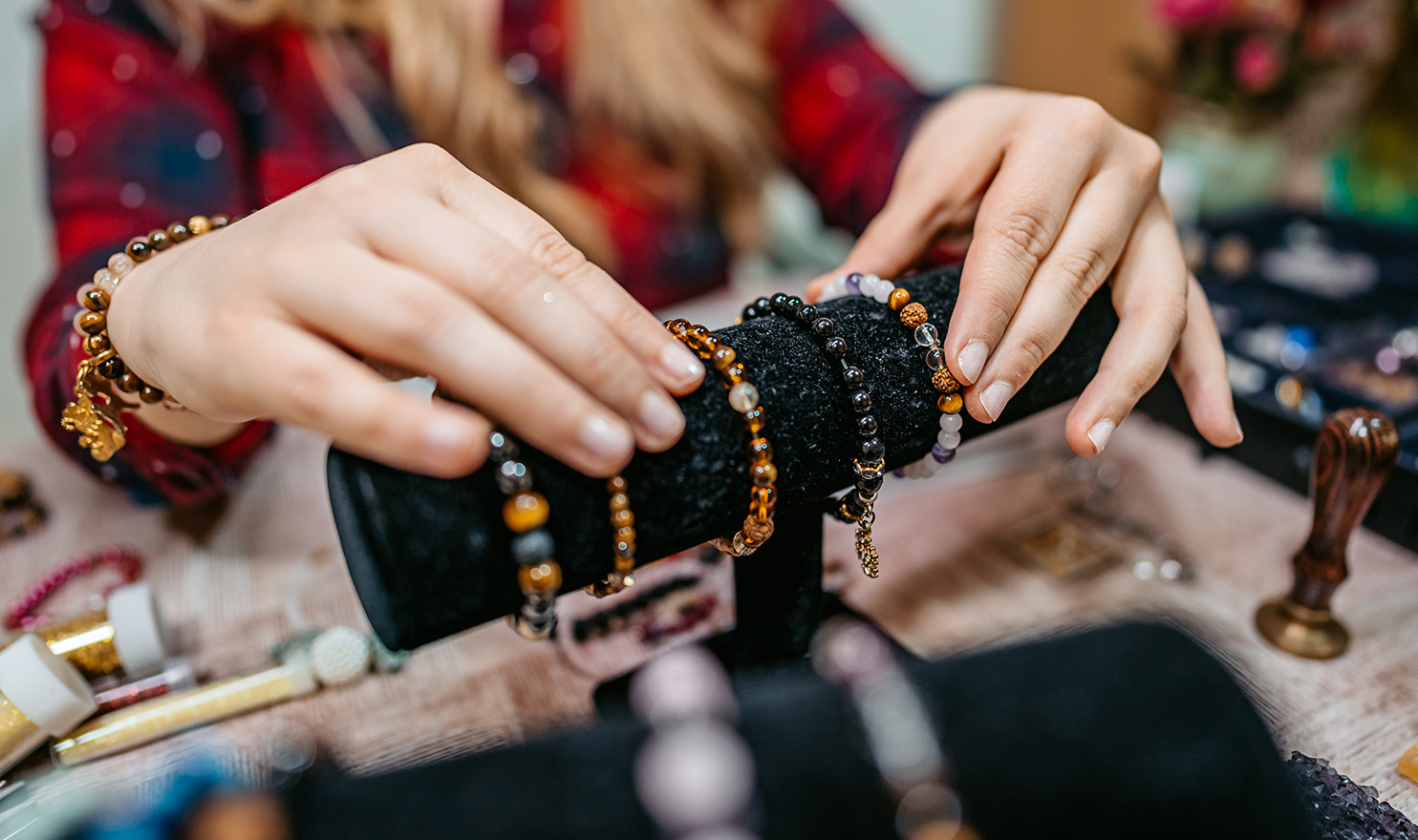 A vendor is placing bracelets to sell on a display stand in their booth.