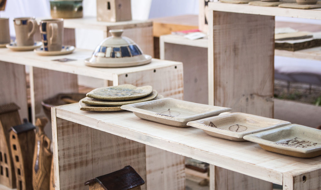 A set of pottery is on display in a craft vendor's booth.