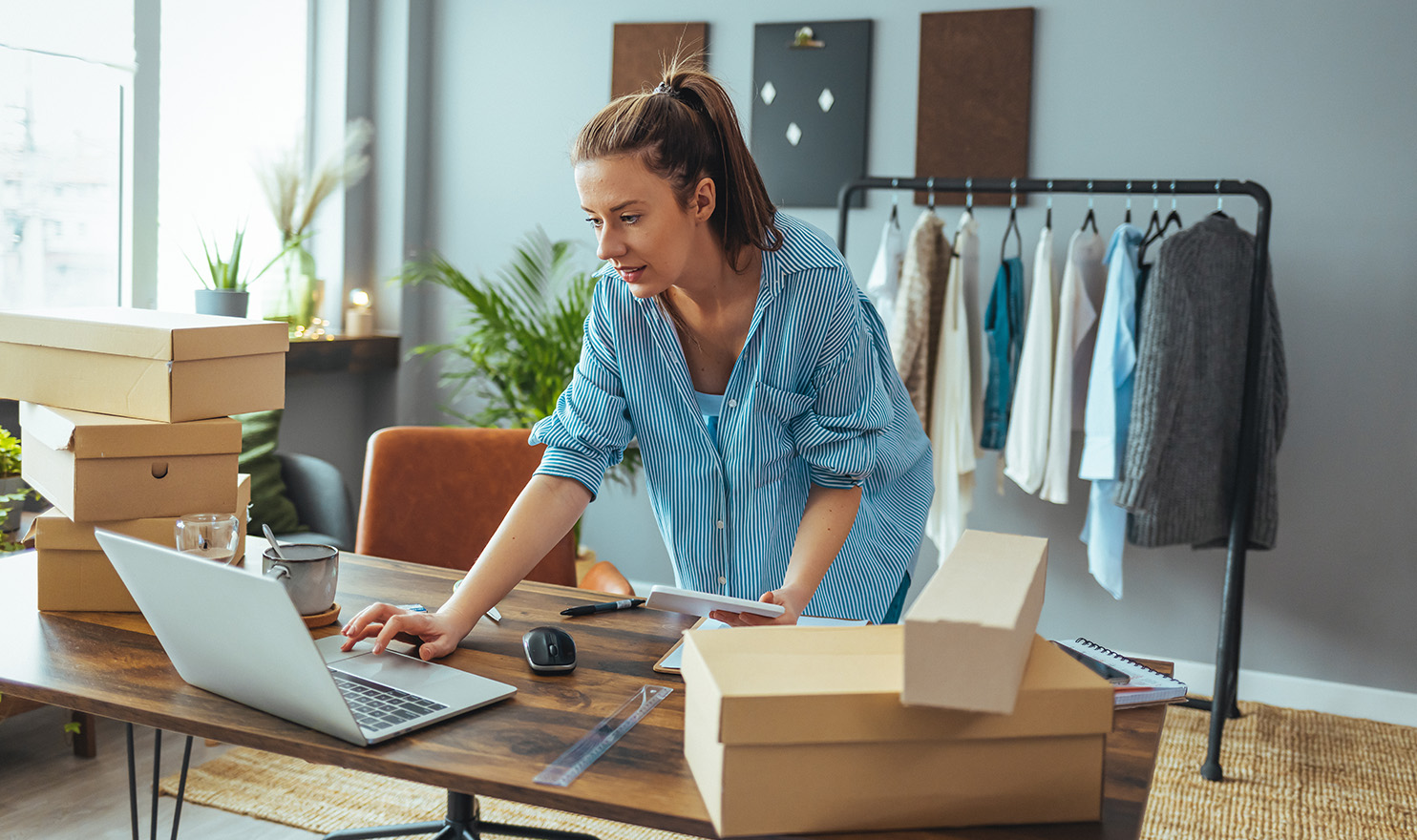 A small business owner is working in her home office on a laptop as she fulfills online orders.