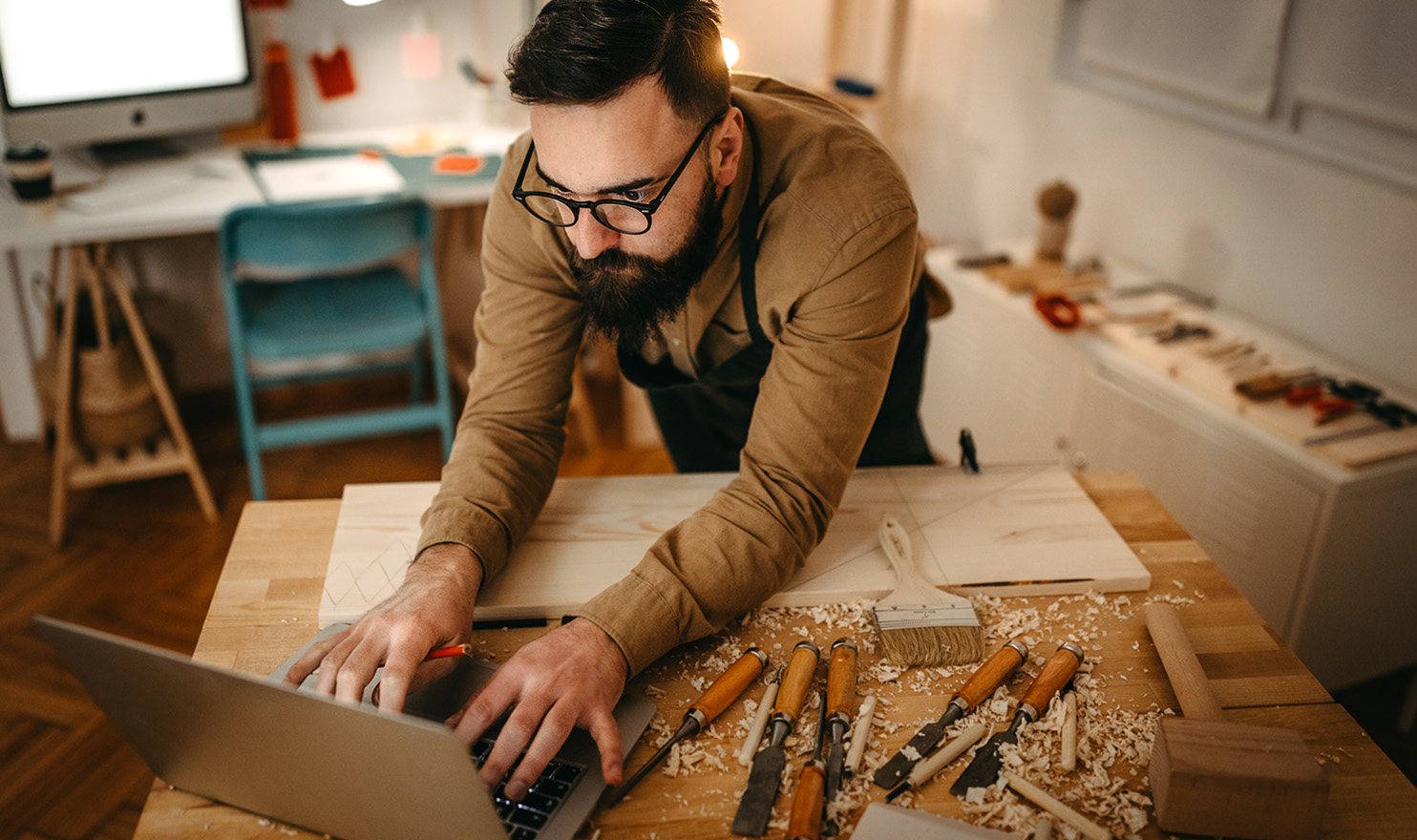 A woodworker is working on his website from his workshop next to his latest project.