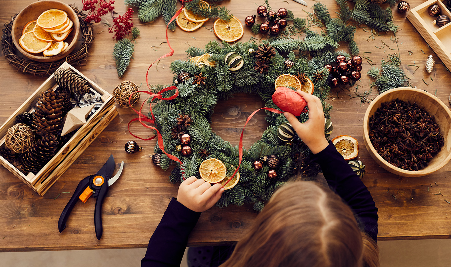 A crafter is making a handmade wreath in preparation for the holiday sales.