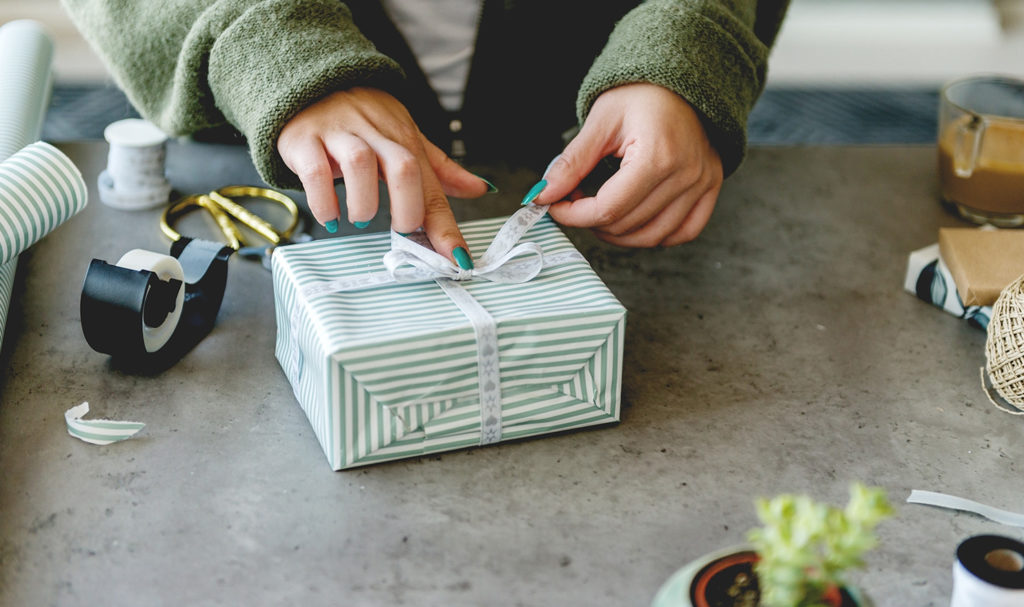 A creative business owner is wrapping up a holiday order in gift wrap.
