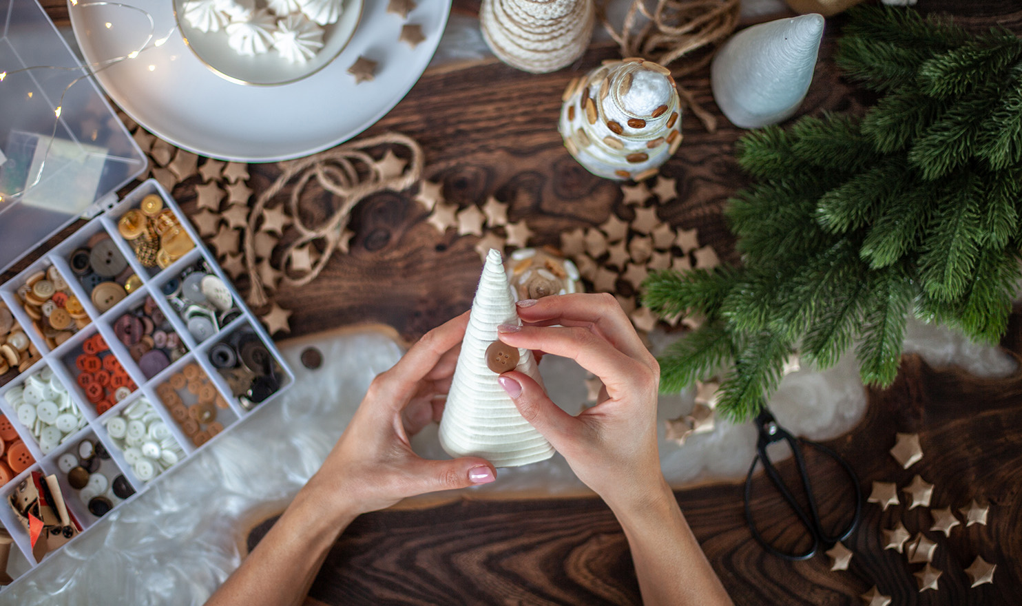 An overhead shot of a crafter putting a button on a handmade Christmas decorations