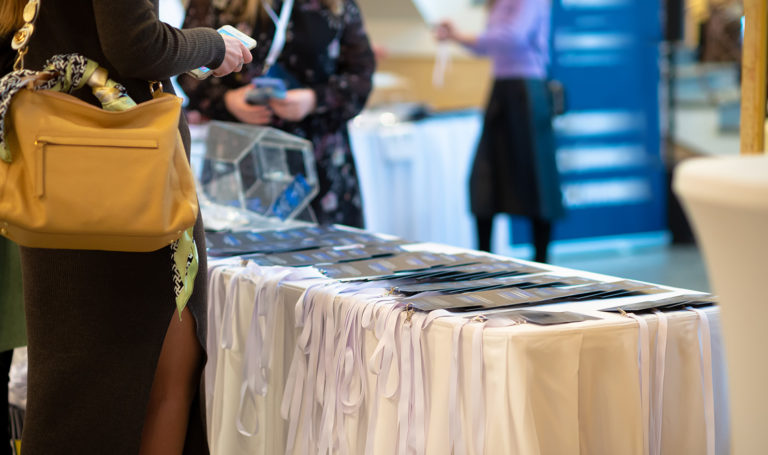 A trade show attendee is looking at brochures for a company in their booth. Having marketing materials like this is a great thing to add to your trade show checklist.