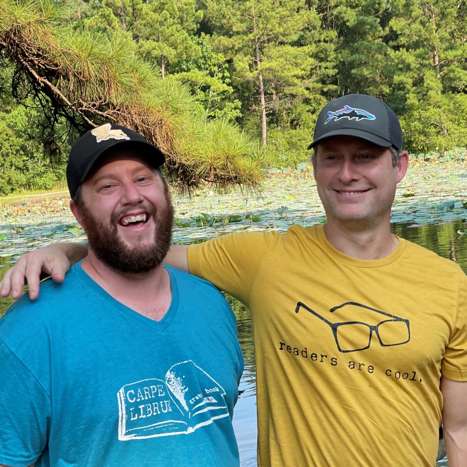 Elizabeth's husband, Robert, is wearing a custom blue tshirt with their business logo on the front. He is standing next to his friend wearing a yellow shirt with their business logo on the front. Elizabeth and Robert's friends will occasionally help them run their business.