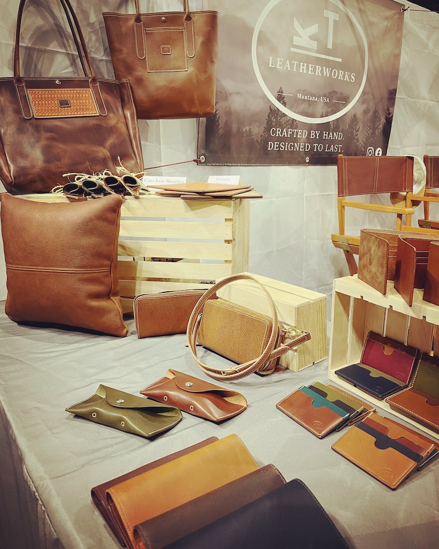 Kelsey Watson's booth display at an event where she showcases the different leather products she handcrafts, such as bookbags, wallets, and journals.