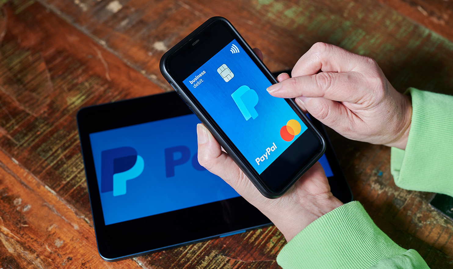 A person is using PayPal on their mobile device and tablet.