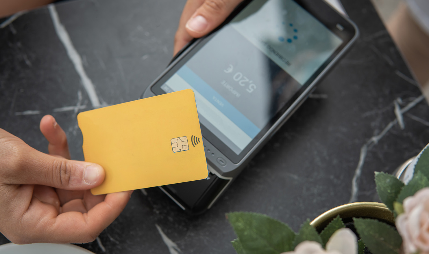 A person completing a tap to pay transaction with their credit card and a mobile payment system.