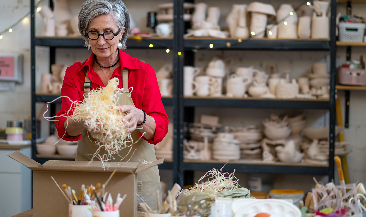 A crafter is carefully packing up an order of handcrafted pottery with added protection so nothing breaks in shipment.