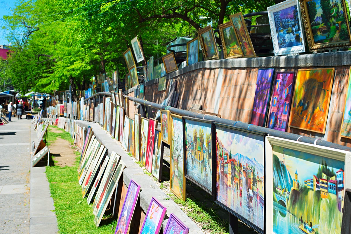 Framed paintings for sale at an outdoor craft event.