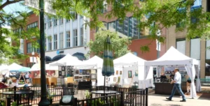 a man walking by an outdoor art festival with white booths